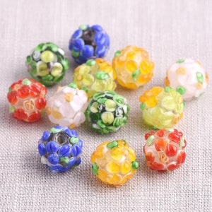 Peut inclure: Assortiment de perles de verre colorées avec des motifs floraux. Les perles sont rondes et présentent une variété de couleurs, notamment le rouge, le bleu, le vert, le jaune et le blanc. Les perles sont parfaites pour la fabrication de bijoux ou d'autres projets d'artisanat.