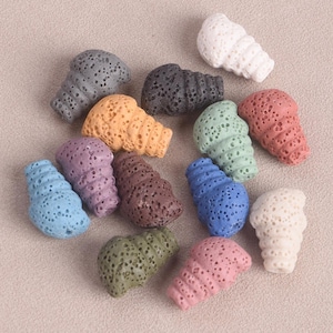 Puede incluir: Surtido de 12 cuentas de roca volcánica en varios colores, incluyendo azul, verde, morado, marrón, naranja, rosa, blanco y gris. Las cuentas tienen todas la forma de una pequeña concha.
