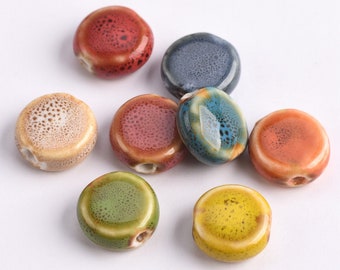May include: Assortment of eight ceramic round beads in various colors, including red, orange, yellow, green, blue, and brown. Each bead has a speckled pattern and a hole for stringing.