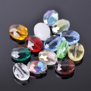 Puede incluir: Surtido de cuentas de vidrio ovaladas en varios colores, incluyendo transparente, verde, rojo, azul y amarillo. Las cuentas tienen un diseño facetado y son perfectas para la elaboración de joyas o manualidades.