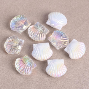 May include: A collection of iridescent seashell-shaped beads. The beads have a pearlescent finish that reflects a rainbow of colors. The shells are a mix of white and clear, with detailed ridged textures. These decorative beads are ideal for crafting and jewelry making.