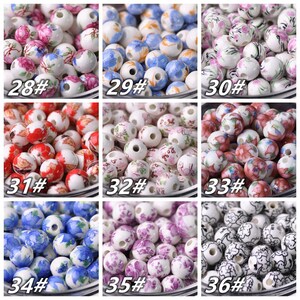 May include: Assortment of 10 different styles of white ceramic beads with floral patterns. The beads are approximately 1 cm in diameter and have a hole in the center for stringing.