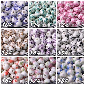 May include: Assortment of 18 ceramic beads with floral patterns. The beads are white with different colored floral designs, including blue, green, pink, purple, brown, red, and blue. The beads are numbered 10 through 18.