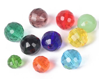 May include: Assortment of faceted glass beads in various colors, including green, red, blue, black, and clear. The beads are round and have a shiny finish.