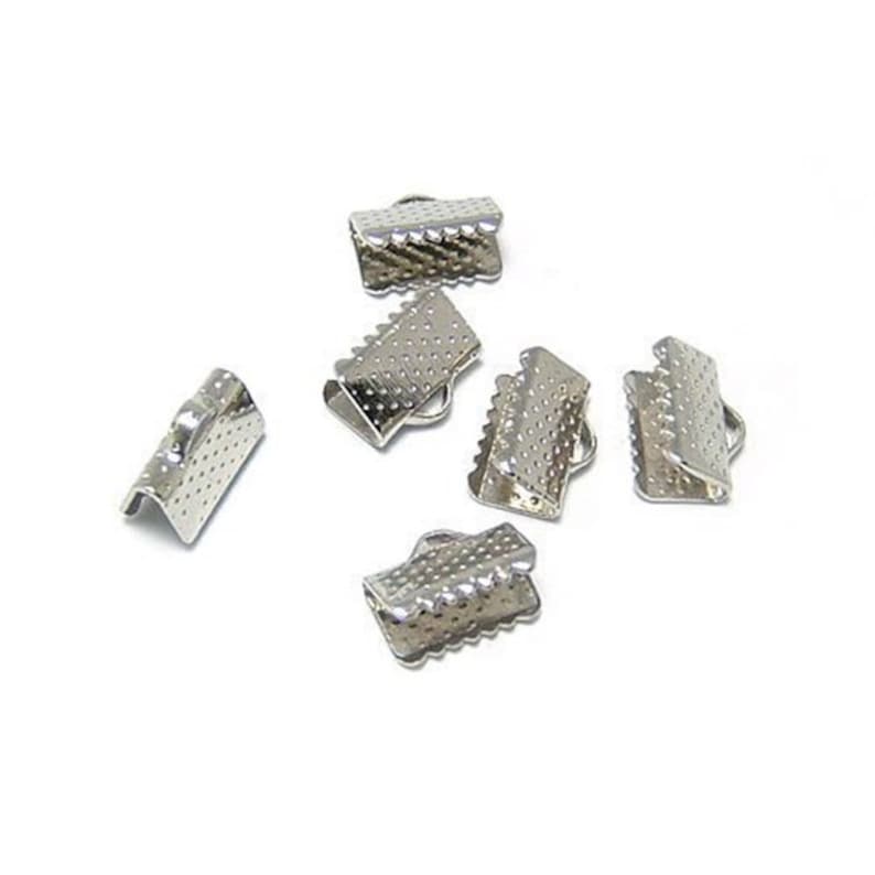 May include: Silver metal clasps for jewelry making. The clasps are small and have a textured surface.