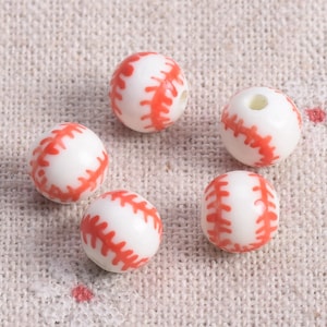 Könnte beinhalten: Fünf weiße Keramik-Baseballperlen mit roten Nähten. Die Perlen haben einen Durchmesser von etwa 2,5 cm.