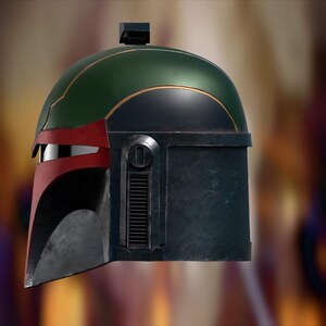 Op de afbeelding: Een zijprofiel van een helm in Mandalorian-stijl met een donkergroene koepel, een rood wanggedeelte en een zwarte onderste voorplaat. De helm is voorzien van een zilverkleurige vizierspleet, een verticale zijventilatie en een kleine rechthoekige bevestiging aan de bovenzijde.