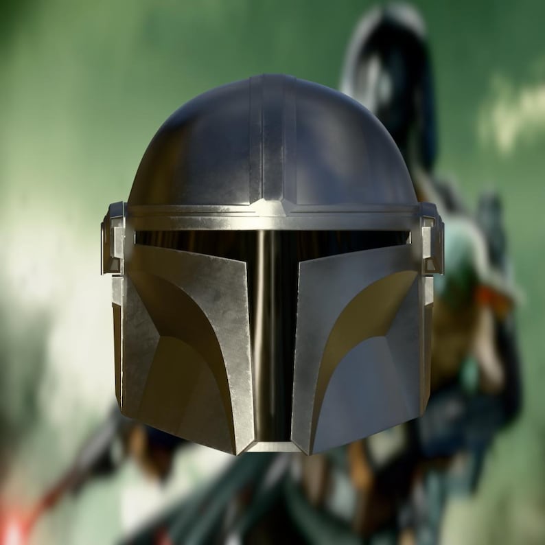 May include: A metallic silver Mandalorian helmet with a T-shaped visor. The helmet has a rounded top and angular features, with a slightly weathered appearance. The background is blurred, suggesting an outdoor setting.