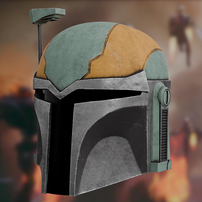 Op de afbeelding: Een verweerde helm met een metallic zilveren voorplaat, een saliegroene koepel met een mosterdgeel accentpaneel en een zwart T-vormig vizier. Een dunne verticale antenne-arm steekt uit aan de rechterkant, bekroond met een kleine rechthoekige sensor.