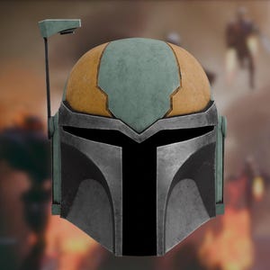 Op de afbeelding: Een verweerde helm met een koepel van afwisselende panelen in gedempt groen en beige. Het voorpaneel is van metallic zilver met een zwart T-vormig vizier en een dunne, verticale antenne aan de rechterkant die omhoog steekt vanaf de slaap.