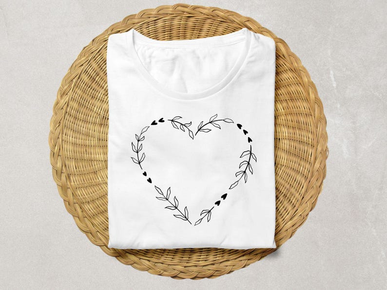 May include: White t-shirt with a black floral heart design. The heart is made of leaves and small hearts.