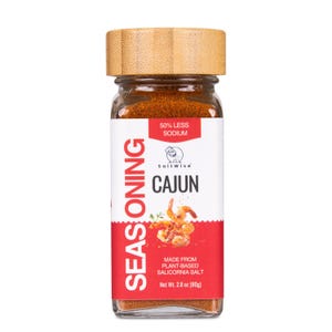 May include: A rectangular glass jar of SaltWise Cajun seasoning with a light brown bamboo lid. The white label features red accents, the text 50% LESS SODIUM, CAJUN, and MADE FROM PLANT-BASED SALICORNIA SALT, with a net weight of 2.8 oz.