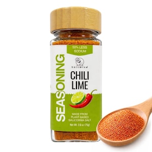 May include: A glass jar of SaltWise Chili Lime seasoning with a wooden lid. The label features a lime and chili pepper illustration. A wooden spoon holds a pile of the seasoning. The label reads "50% Less Sodium" and "Net Wt. 2.6 oz (75g)."