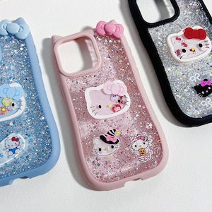 May include: Three phone cases with glitter and Hello Kitty designs. One case is blue, one is pink, and one is black. Each case has a bow at the top and several Hello Kitty character stickers.