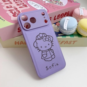 Puede incluir: Una funda de tel&eacute;fono lavanda con un dise&ntilde;o de Hello Kitty y el nombre "Sofia" impreso debajo. La funda tiene una apariencia texturizada y un protector de lente de c&aacute;mara. El fondo incluye una caja de cereales rosa y macarons decorativos.