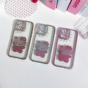 Pu&ograve; includere: Tre custodie per telefono trasparenti con un design Hello Kitty e un anello porta-anello con gioielli. Le custodie sono rosa, oro e argento.