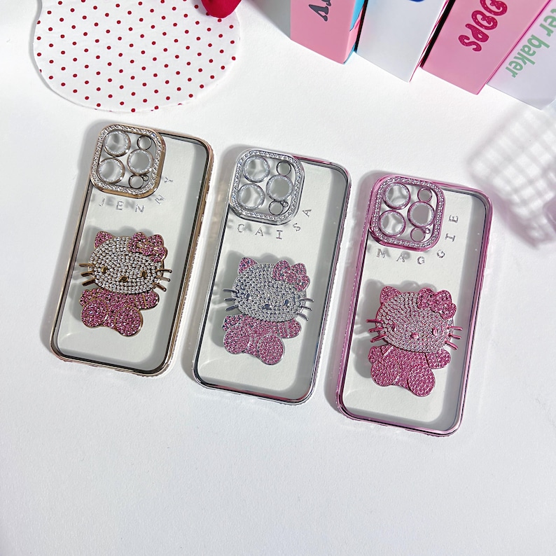 Pu&ograve; includere: Tre custodie per telefono trasparenti con un design Hello Kitty e un anello porta-anello con gioielli. Le custodie sono rosa, oro e argento.