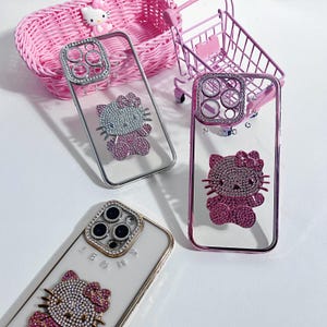 Pu&ograve; includere: Tre custodie per telefono trasparenti con strass e un design Hello Kitty. Le custodie sono rosa, argento e bianche. Le custodie hanno un rivestimento per l'obiettivo della fotocamera rialzato con strass.