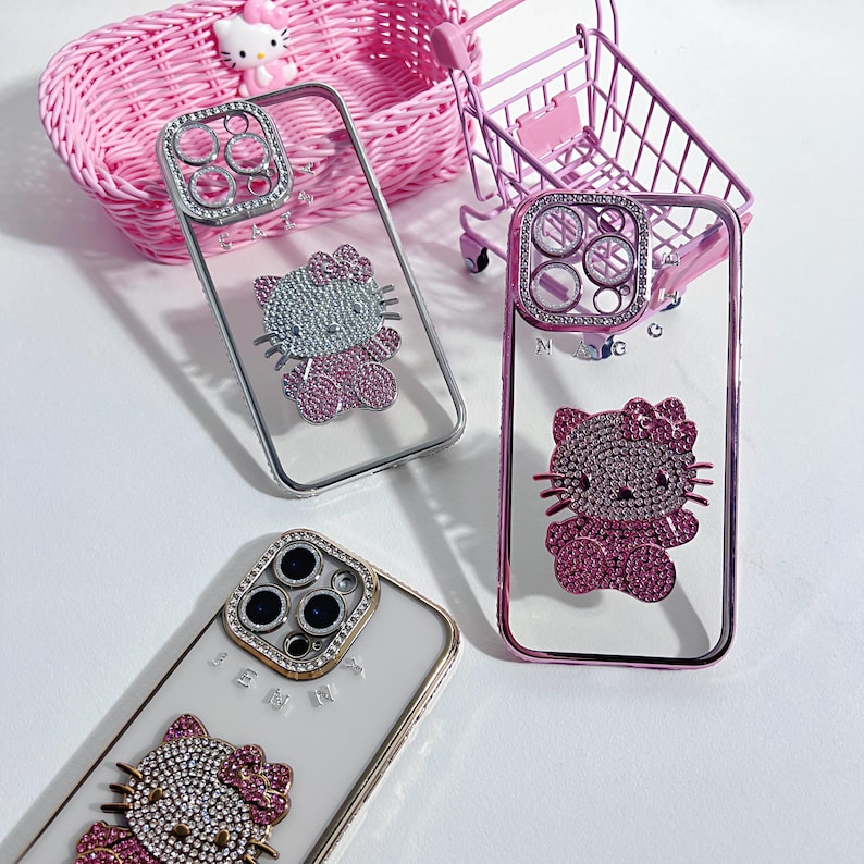 Pu&ograve; includere: Tre custodie per telefono trasparenti con strass e un design Hello Kitty. Le custodie sono rosa, argento e bianche. Le custodie hanno un rivestimento per l'obiettivo della fotocamera rialzato con strass.