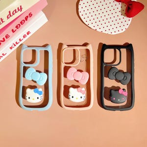 Puede incluir: Tres fundas para tel&eacute;fono con diferentes dise&ntilde;os de Hello Kitty en colores distintos. Las fundas son transparentes y muestran el objetivo de la c&aacute;mara del tel&eacute;fono. Las fundas son azules, rosas y negras.