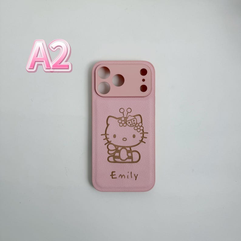 Puede incluir: Una funda de tel&eacute;fono rosa con un dise&ntilde;o de Hello Kitty y el nombre "Emily" grabado en dorado. La funda tiene recortes para la c&aacute;mara y los botones. El fondo es gris claro.