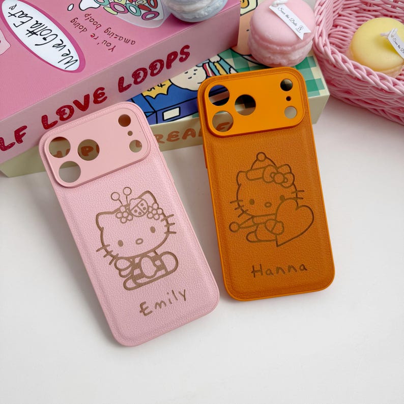 Pu&ograve; includere: Due custodie per telefono, una rosa e una arancione, ciascuna con un design di Hello Kitty. La custodia rosa ha il nome "Emily" e quella arancione "Hanna". Entrambe le custodie hanno un ritaglio per la fotocamera.