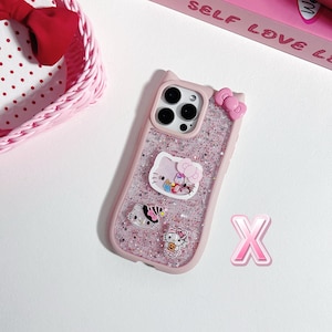 Op de afbeelding: Roze glitter telefoonhoesje met Hello Kitty-ontwerpen. De hoes heeft een strik en verschillende Hello Kitty-personageontwerpen. De hoes heeft een roze rand en een doorzichtige achterkant met roze glitter.