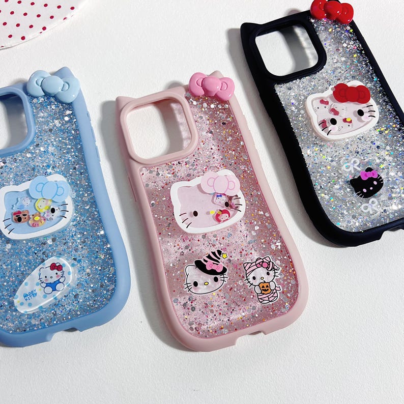 May include: Three phone cases with glitter and Hello Kitty designs. One case is blue, one is pink, and one is black. Each case has a bow at the top and several Hello Kitty character stickers.