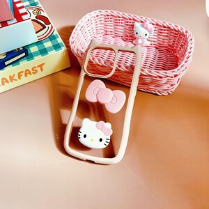 Puede incluir: Una funda transparente para tel&eacute;fono con un lazo rosa y un dise&ntilde;o de Hello Kitty. La funda est&aacute; hecha de un material flexible y tiene un borde elevado alrededor de la lente de la c&aacute;mara para protegerla de los ara&ntilde;azos.