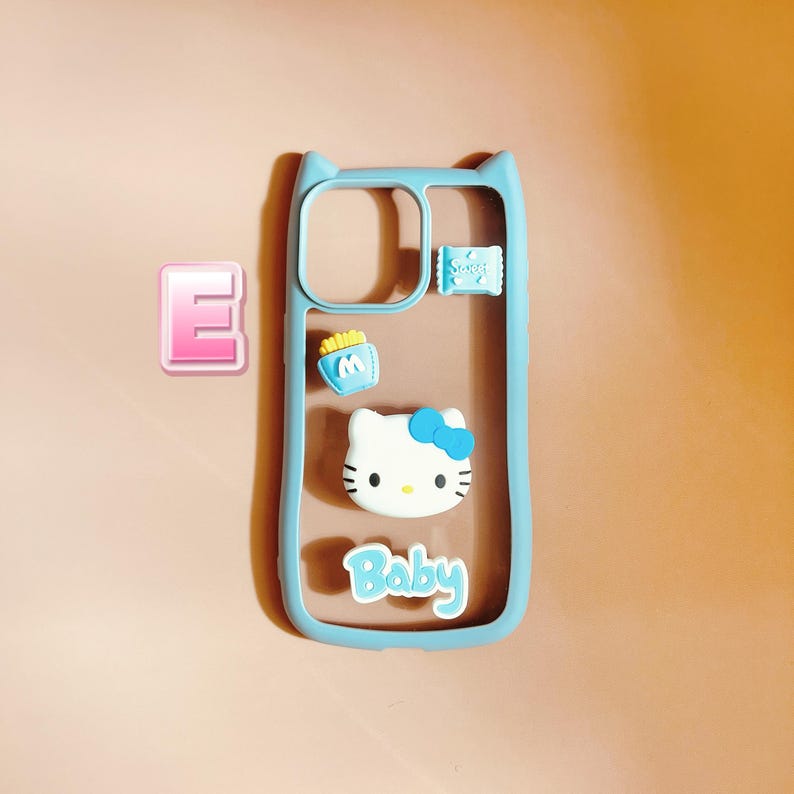 Op de afbeelding: Een lichtblauwe telefoonhoes met een transparante achterkant. De hoes heeft een Hello Kitty-personage, een klein blauw tasje met frietjes en het woord "Baby" op de achterkant.