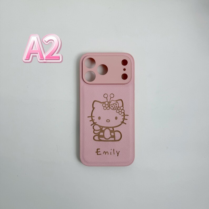 May include: A pink phone case with a Hello Kitty design, a bow, and the name "Emily" engraved. The case has a lighter pink section at the top for the camera. The case is designed for a smartphone.