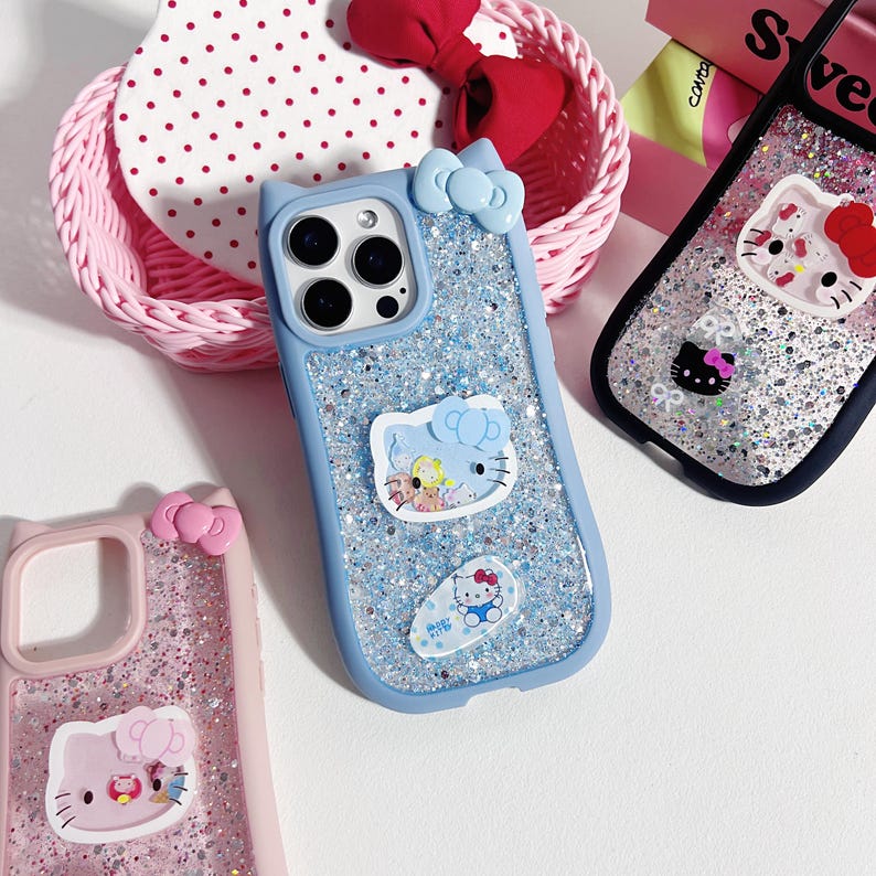 May include: A collection of phone cases featuring glitter and cartoon character designs. The cases are in various colors, including blue and pink, and feature a bow and cat ear design. The cases have a glittery background and cartoon character stickers.