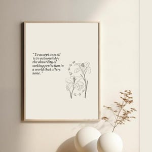 May include: A black and white printable art print with a quote about self-acceptance and a line drawing of two lilies with stars. The quote reads "To accept oneself is to acknowledge the absurdity of seeking perfection in a world that offers none."