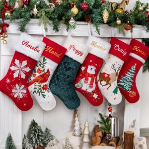 May include: Six Christmas stockings hang from a white mantel, each with a name embroidered on the white cuff. The stockings are red, green, and white, with festive designs like snowflakes, a cardinal, a polar bear, and a Christmas tree.