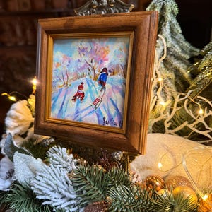 May include: A white ceramic mug with a black handle and the text "But First, Coffee" in a bold, black font. The mug is set against a blurred background, suggesting a cozy setting.