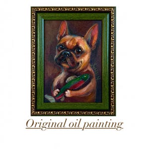 May include: An original oil painting in a dark green and gold ornate frame depicting a brown French bulldog holding a green and red fish. The painting features a dark brown background and the signature Julia N on the right side of the canvas.