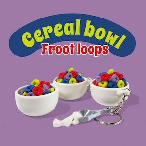 Könnte beinhalten: Miniatur-Keramik-Müslischalen in Weiß, gefüllt mit bunten Froot Loops-Cerealien. Ein Schlüsselanhänger mit einem Löffel ist an einer Schale befestigt. Das Bild enthält den Text "cereal bowl" und "Froot loops".