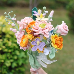 May include: A crocheted bouquet of flowers in shades of pink, yellow, orange, and purple. The bouquet includes a variety of flower types, including roses, daisies, and lilies.