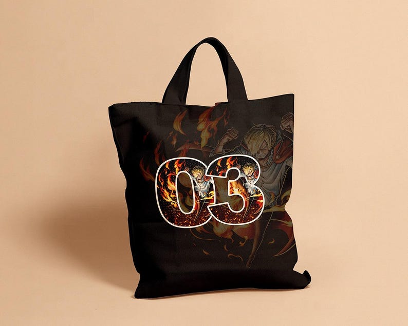 May include: Black tote bag featuring a graphic of a character with blonde hair and the number "03" in a fiery design. The background shows a fiery scene with other characters. The bag has black handles.
