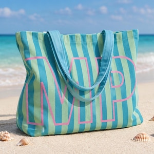 May include: A tote bag featuring vertical stripes in alternating shades of teal and light green. The bag has two matching teal shoulder straps and displays the large pink outlined letters "VIP" printed across the front surface of the fabric.