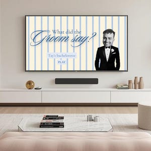 May include: A digital game screen titled What did the Groom say? featuring a light blue and cream vertical striped background, a cutout of a person in a tuxedo, and text reading Tay's bachelorette and PLAY, displayed on a wall-mounted television.