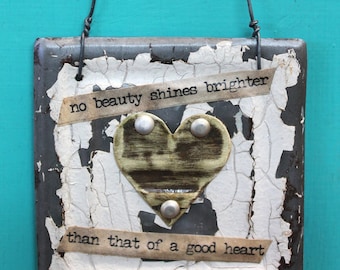 wall decor - hanging white ceiling tile with brass heart and  words "no beauty shines brighter than that of a good heart"