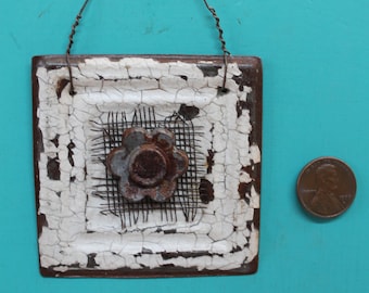 wall decor - hanging white ceiling tile with rusty flower on old rusty screen