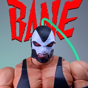 Puede incluir: Figura de acción del villano de DC Comics, Bane, con una máscara en blanco y negro, ojos rojos y un atuendo en blanco y negro. La palabra "BANE" está escrita en letras rojas grandes encima de la figura. Un tubo verde está conectado a la máscara.