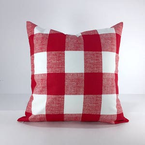 May include: Red and white buffalo check pillow cover. The pillow cover is made of a soft, textured fabric.