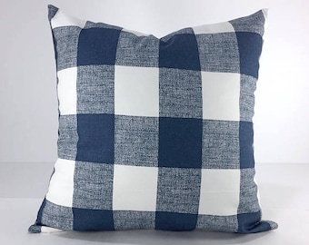 May include: A navy blue and white buffalo plaid pillow cover. The pillow cover is made of a soft, textured fabric.