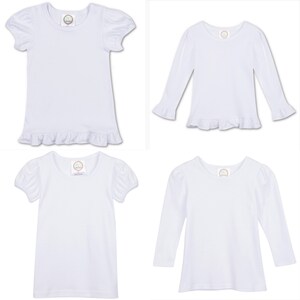 May include: Four white t-shirts with ruffled hems. Two shirts have short sleeves with puffed shoulders and two shirts have long sleeves with ruffled cuffs.