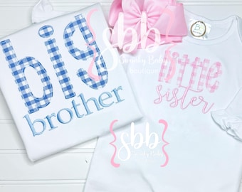 May include: Two white t-shirts with blue and pink gingham embroidery. The larger shirt says "big brother" and the smaller shirt says "little sister".