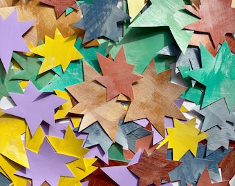 May include: A collection of multi-pointed star-shaped cutouts in various colors including yellow, lavender, green, blue, and metallic bronze. The stars feature visible brushstroke textures and are layered over one another in a dense, overlapping arrangement.