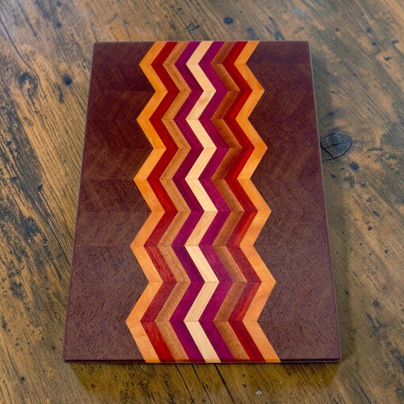 A named, multi-species hardwood mosaic (walnut, cherry, padauk, maple) made by a named maker in Kentucky — this is actual woodworking craft, not a laser-engraved commodity board.